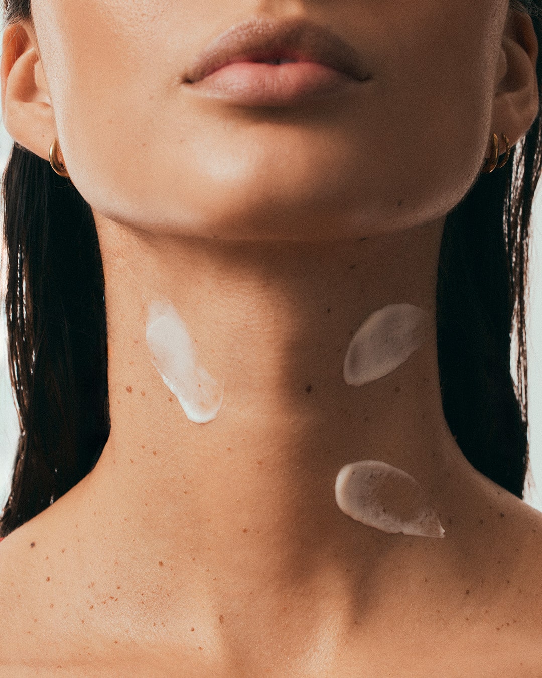 woman with neck cream swipes on her neck