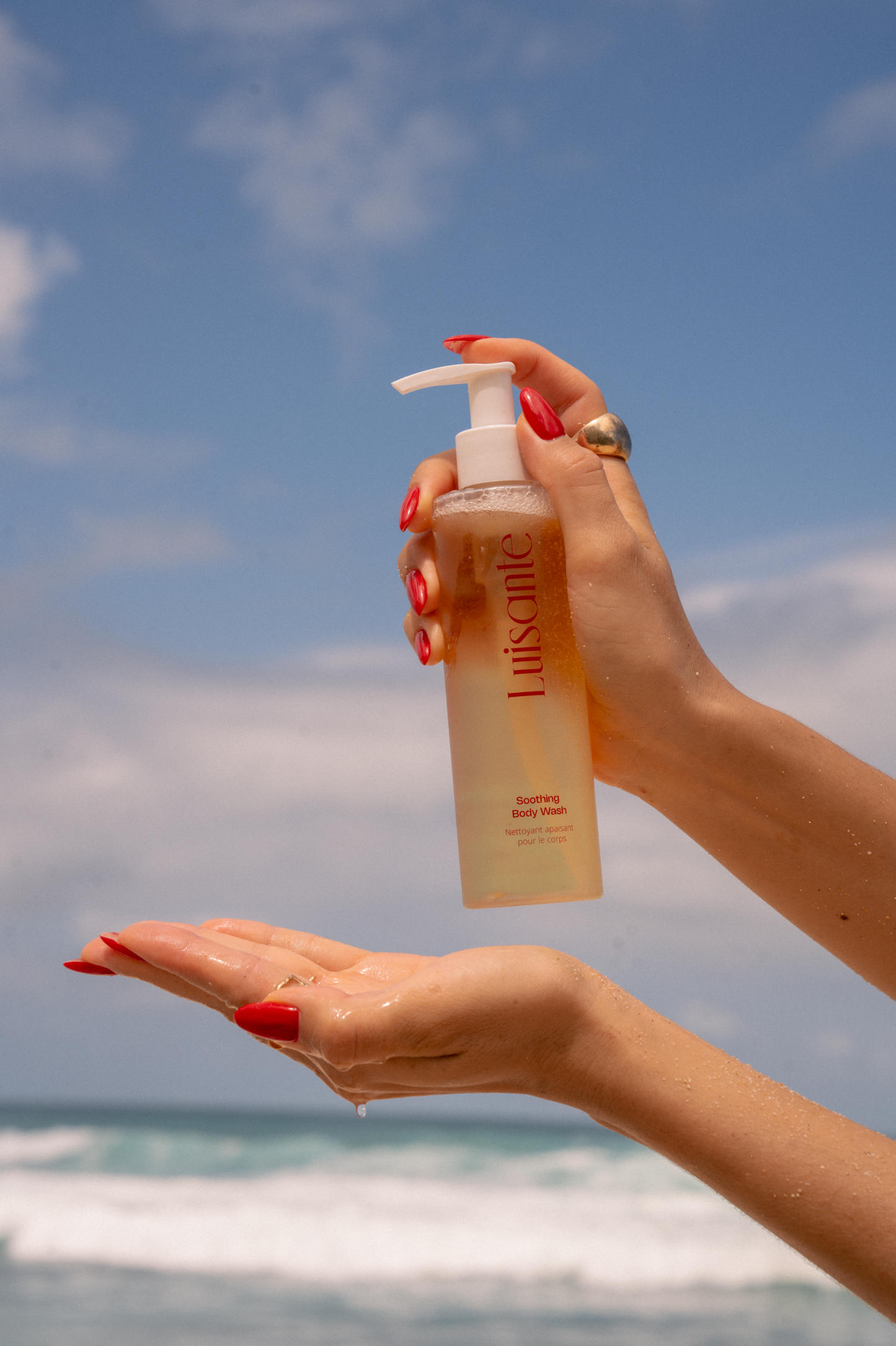 Luisante Soothing Body Wash Pump Bottle Held Over Open Palm at the Beach